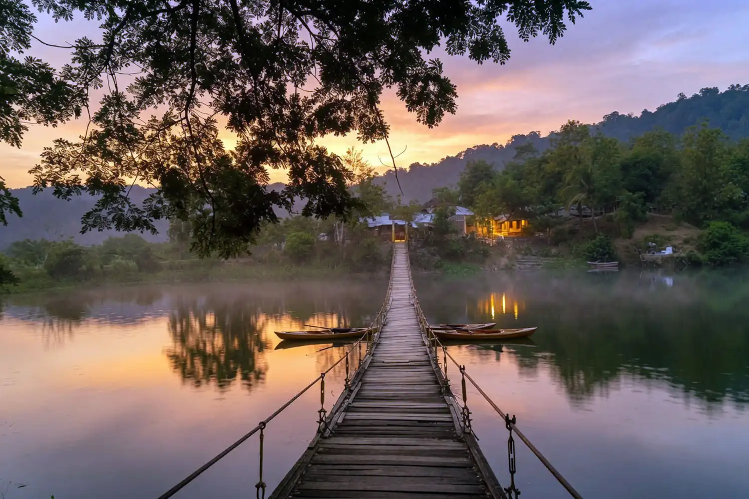 Calm evening over Naikhongchhari Lake with small kayaks on the water and warm light over the forested hills