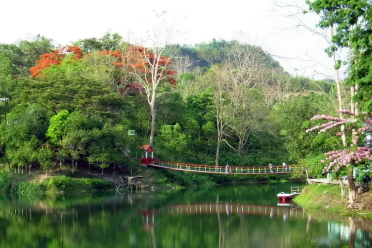 Calm blue-green water of Prantik Lake in Bandarban ringed by forested hills under a clear sky