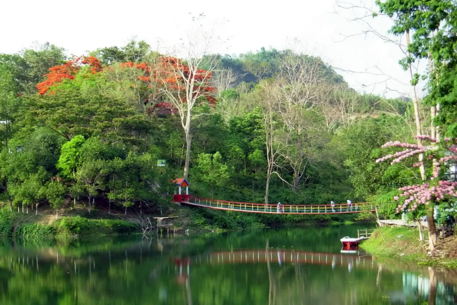 Calm blue-green water of Prantik Lake in Bandarban ringed by forested hills under a clear sky