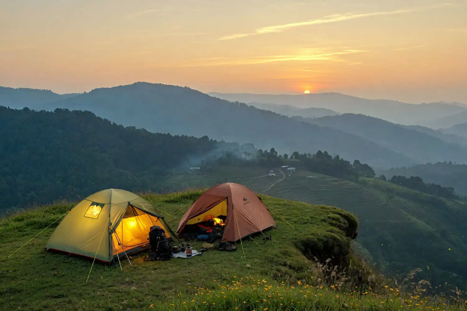 Camping tents set up on a grassy hilltop above the forest at dusk near Thankowain Waterfall in Bandarban