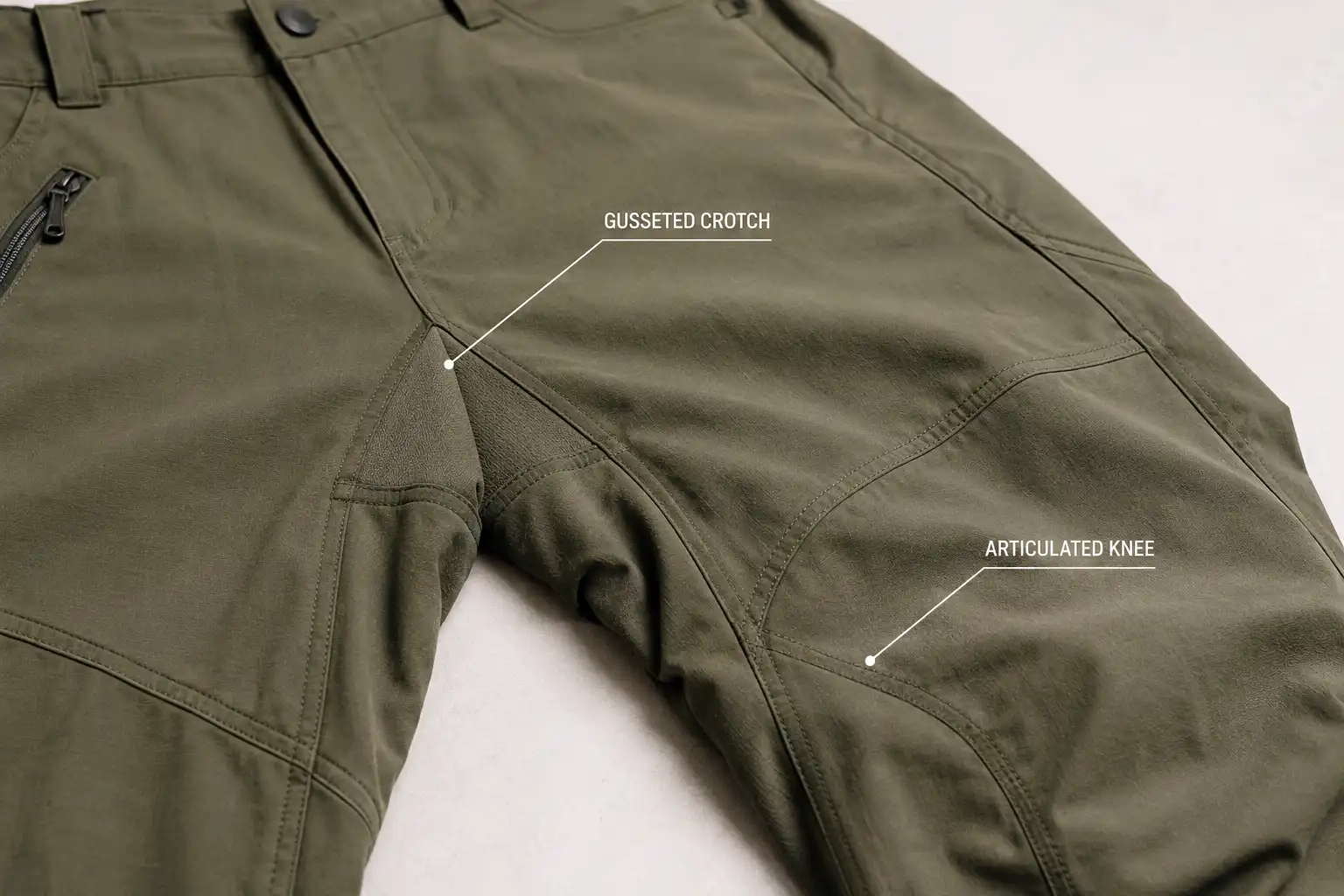 Close up of technical hiking pants showing the diamond shaped gusset panel at the inner thigh and the curved articulated seams shaping the knee