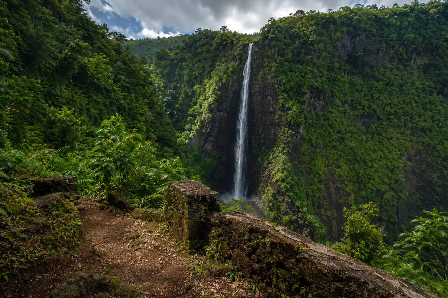 Fautaua waterfall dropping into a steep basalt gorge viewed from the upper trail above Papeete