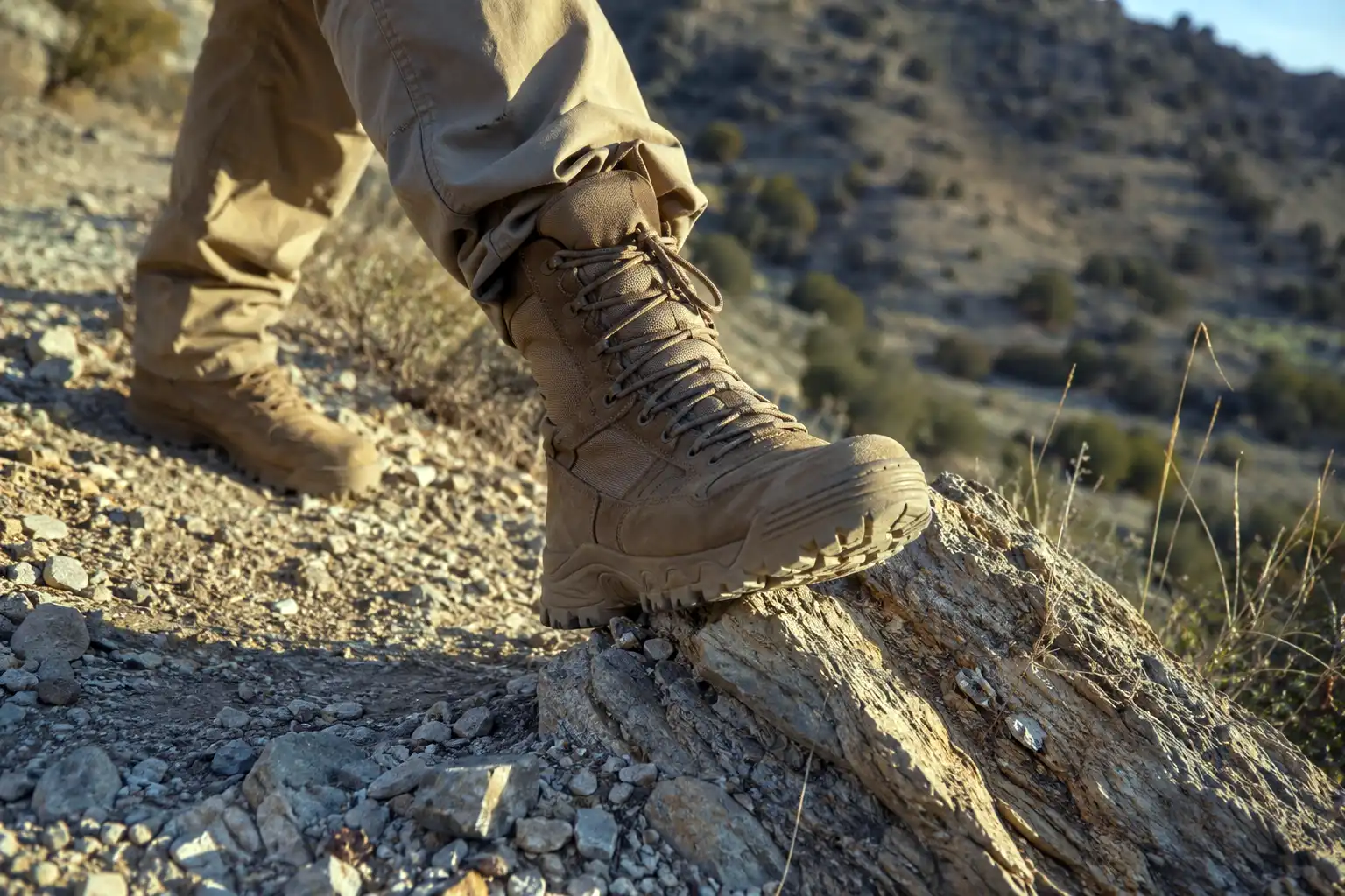 Close view of a hiker's ankle and boot as they step down onto loose uneven rock on a steep trail
