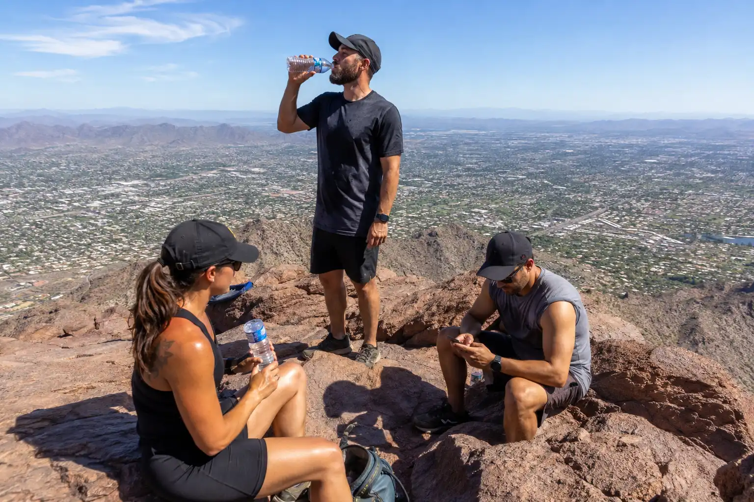 Hikers sitting on rocks at the 2,704 foot Camelback Mountain summit with a wide view over Phoenix