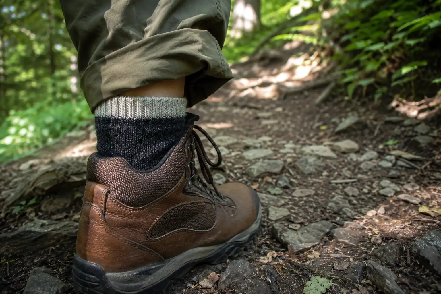 Close up of a hiker's ankle showing a wool blend hiking sock sitting above the boot collar to stop the boot edge rubbing the skin