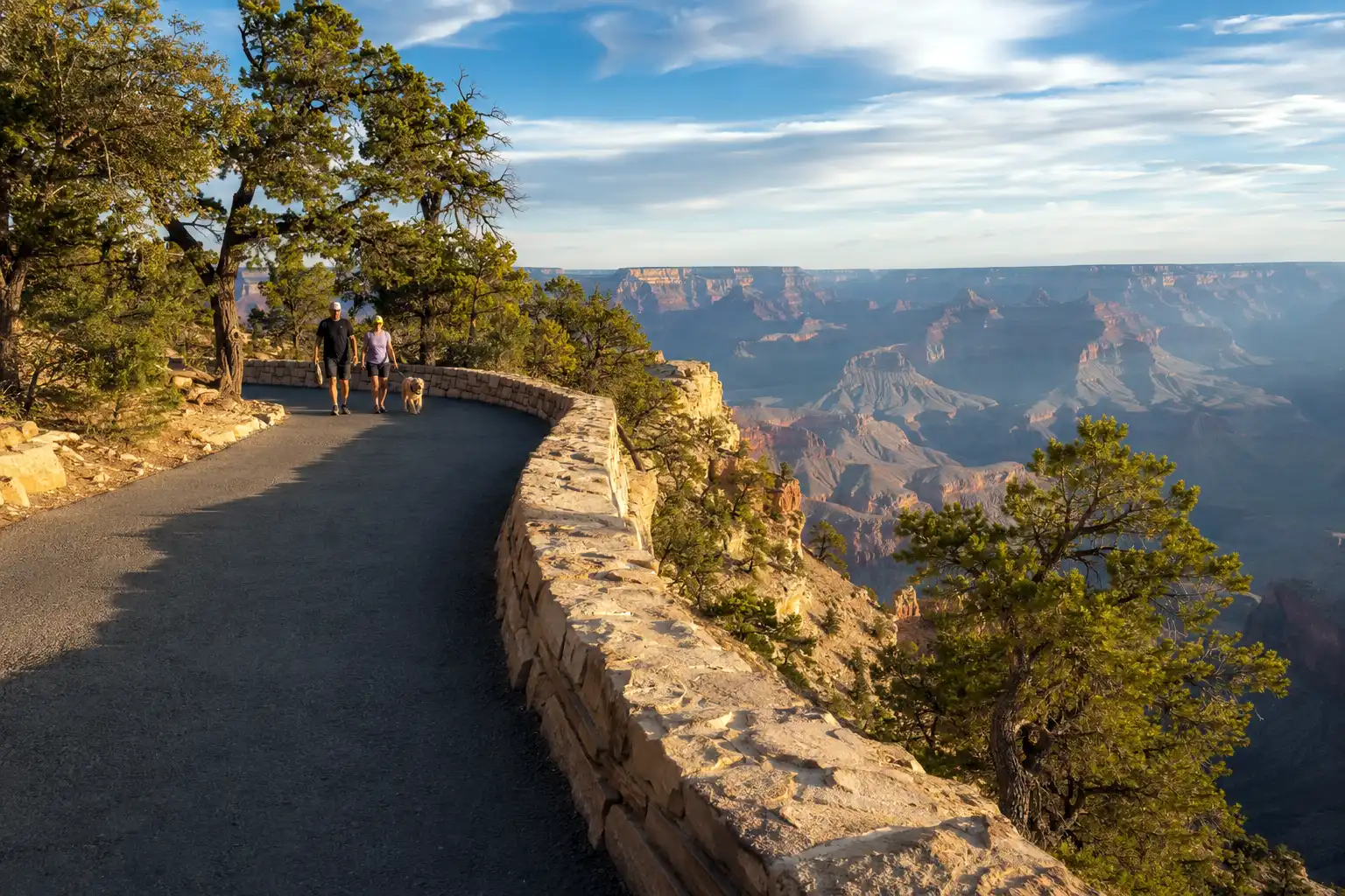 Flat paved section of the Grand Canyon Rim Trail running past a viewpoint with the canyon opening out below