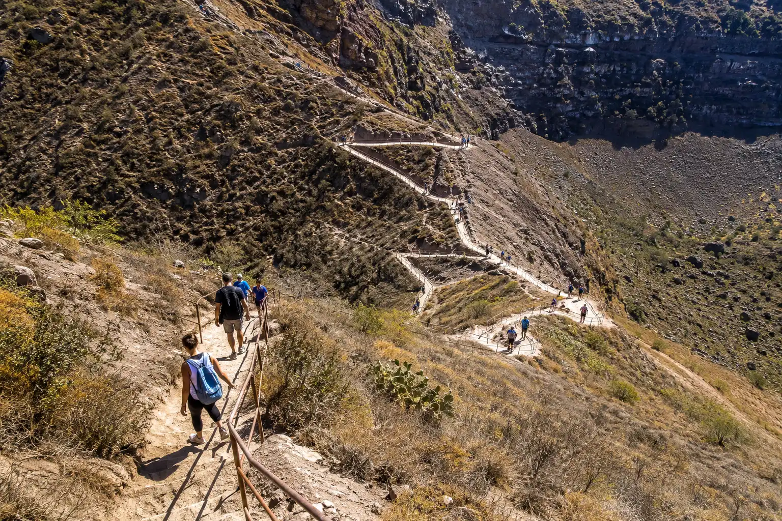 Hikers walking a series of switchbacks on the dusty tuff trail up the inside wall of Diamond Head crater