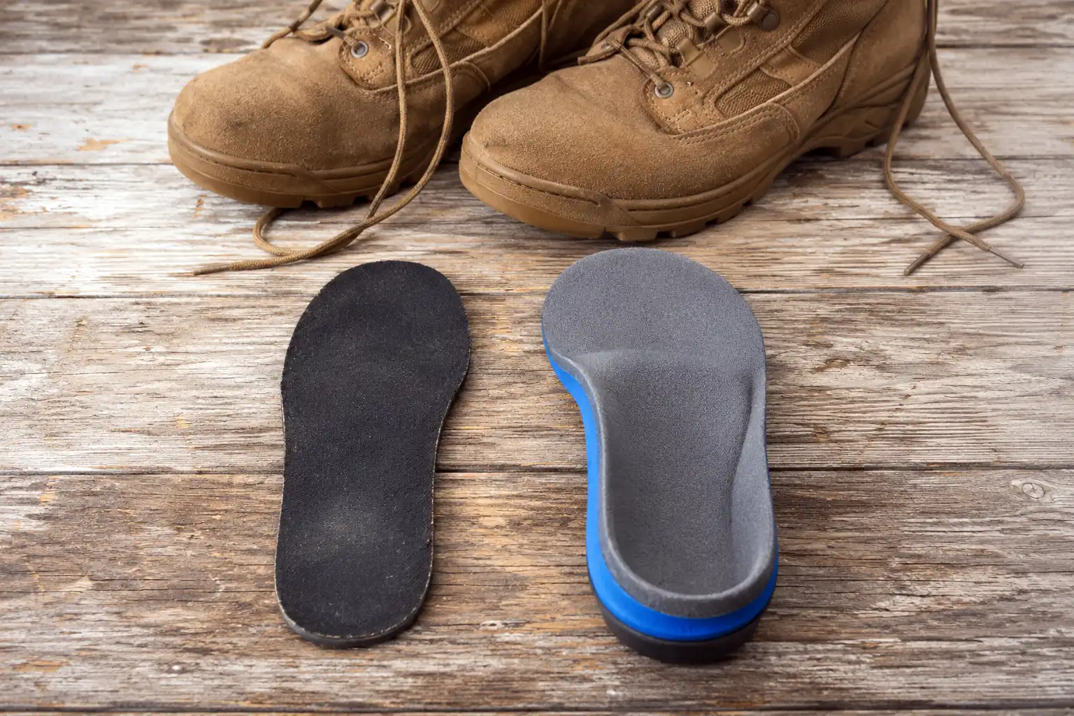Flat military boot insole shown beside a thicker contoured aftermarket insole to compare cushioning and arch shape