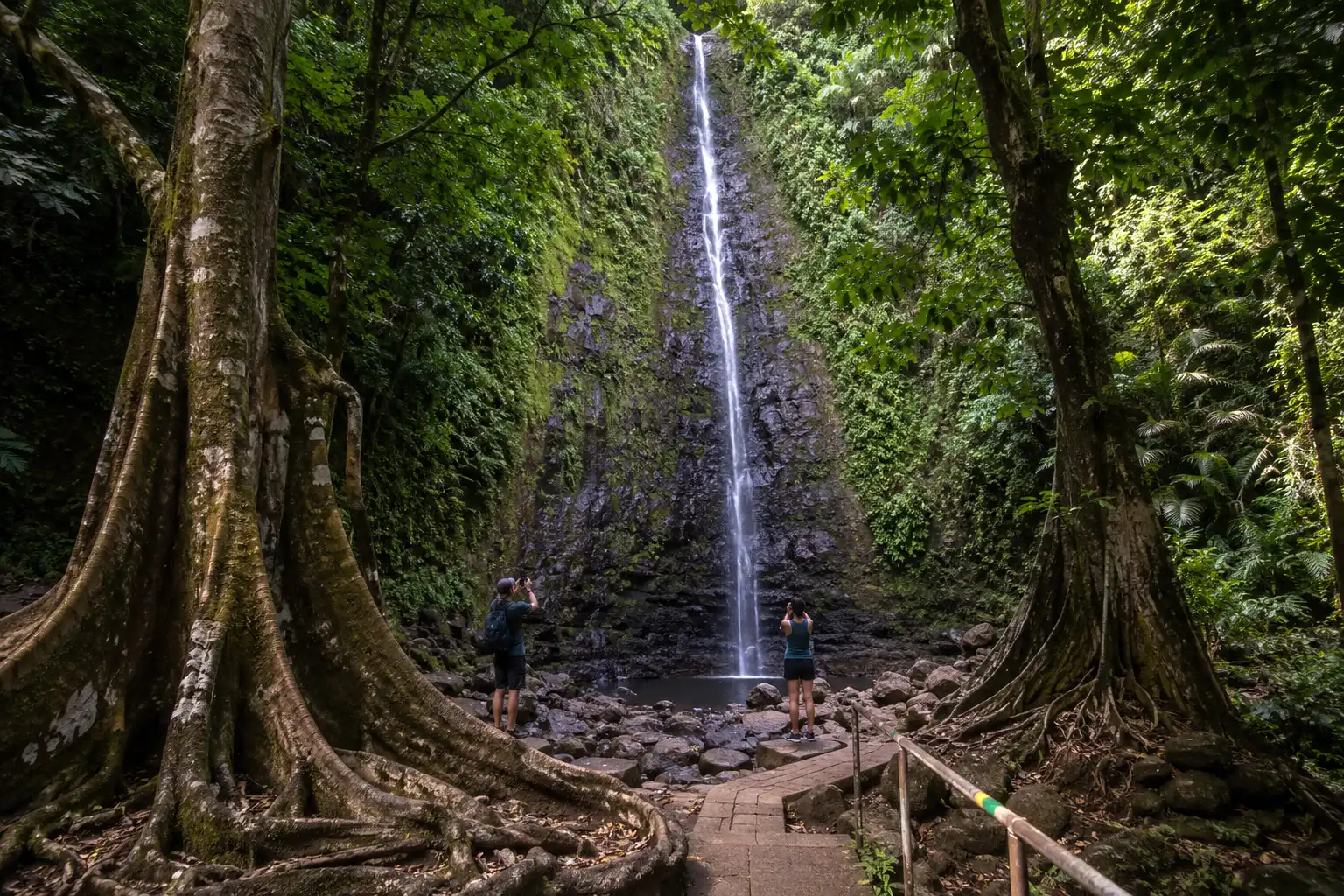 Vaimahuta waterfall falling into a shallow pool at the end of a short paved path at Faarumai