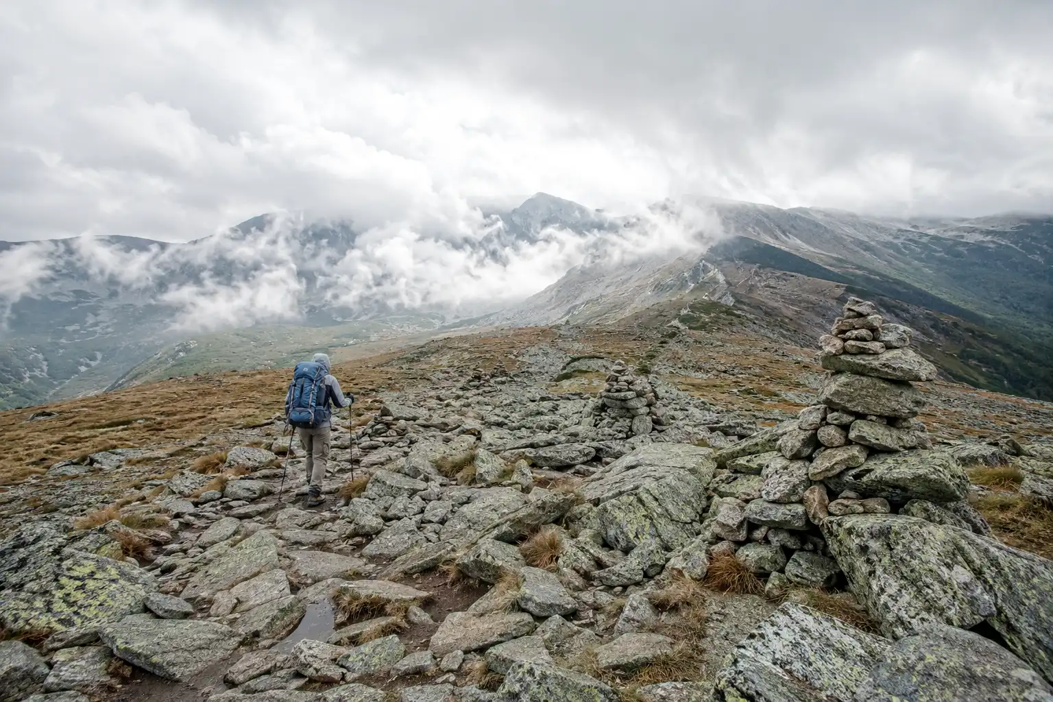Hiker crossing an exposed rocky alpine ridge in the White Mountains where Appalachian Trail daily mileage drops sharply