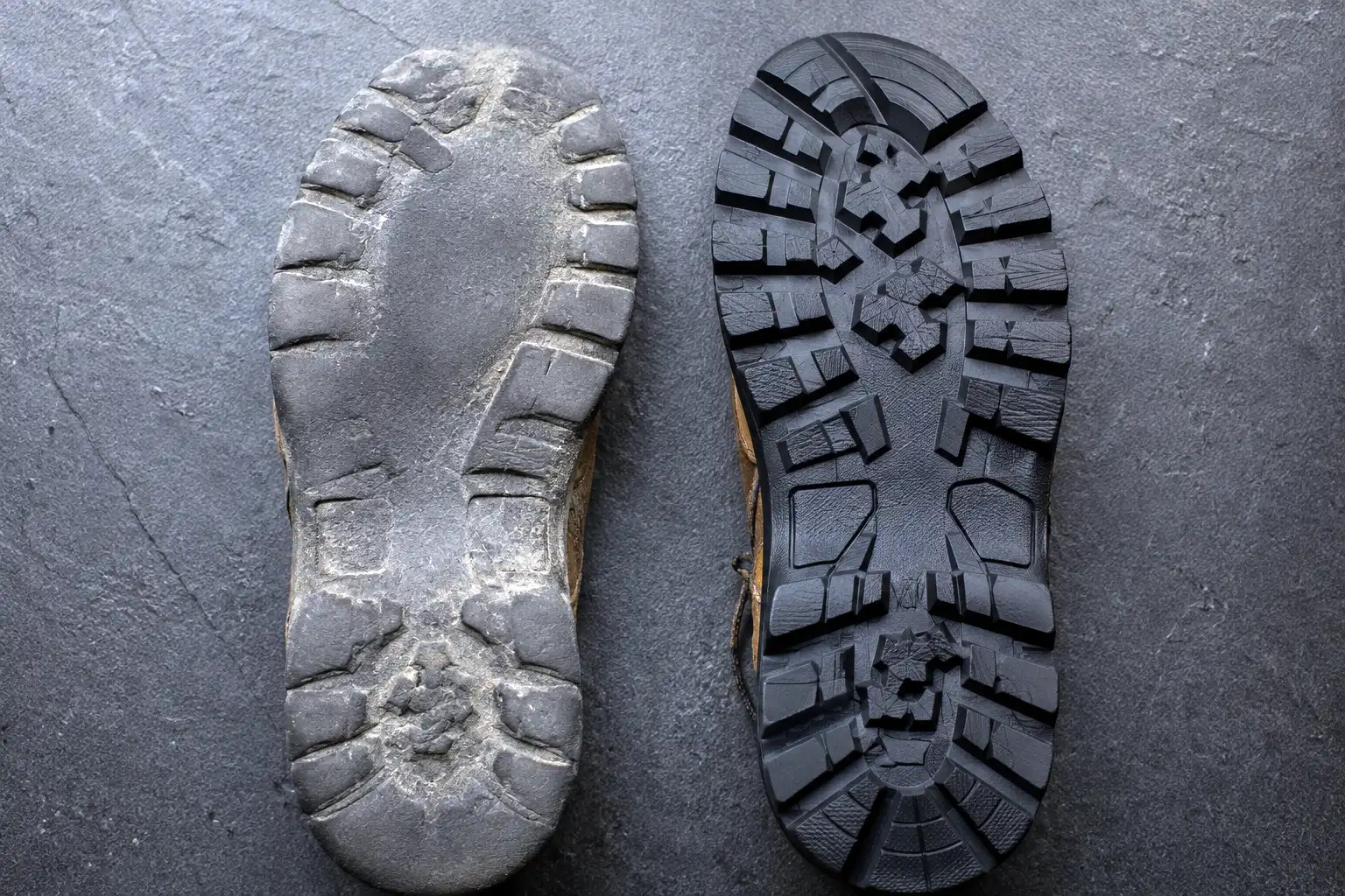 Close-up comparison of a hiking boot outsole with lugs rounded off by pavement next to a boot outsole with sharp new lugs